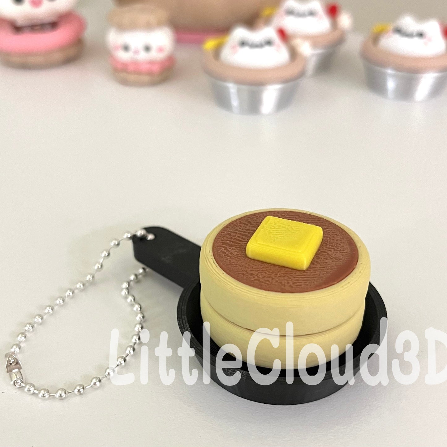 Miniature cake-shaped keychain with a chain on a white surface