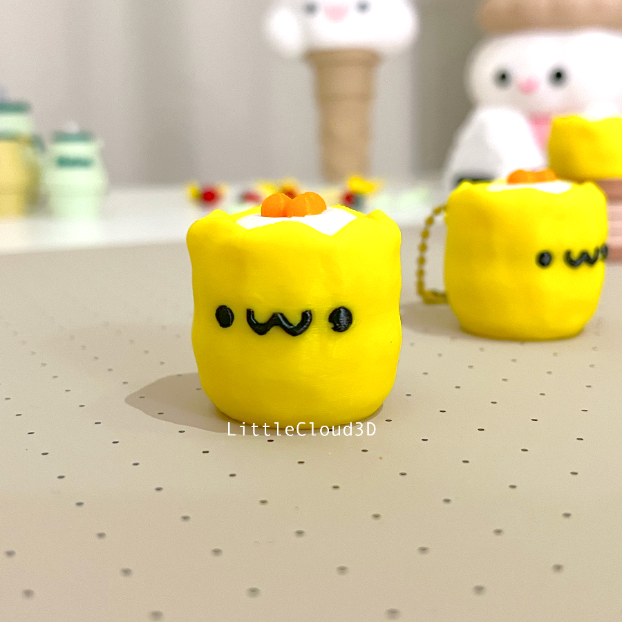 Two yellow 3d printed siu mai clickers with smiley faces on them.